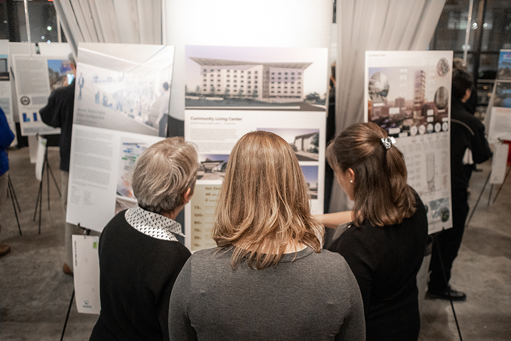 Three attendees discuss a showboard at Green Building showcase